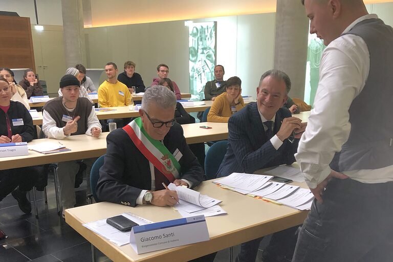 Maurer David und Giacomo Santi, Bürgermeister der Stadt Volterra, unterzeichnen den Vertrag.