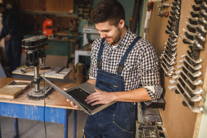 Young carpenter working on a laptop in his workshop. Schlagwort(e): workshop, carpentry, occupation, carpenter, laptop, professional, craftsman, handyman, industry, craft, job, timber, lumber, woodwork, handmade, tools, old, business, manual, worker, plan, expertise, computer, pursuit, art, person, careers, equipment, activity, craftsmanship, talent, decoration, lifestyle, wooden, classic, handicraft, design, skill, capability, career, style, networking, working, woodworker, online, using, smiling, workman, indoors, workshop, carpentry, occupation, carpenter, laptop, professional, craftsman, handyman, industry, craft, job, timber, lumber, woodwork, handmade, tools, old, business, manual, worker, plan, expertise, computer, pursuit, art, person, careers, equipment, activity, craftsmanship, talent, decoration, lifestyle, wooden, classic, handicraft, design, skill, capability, career, style, networking, working, woodworker, online, using, smiling, workman, indoors