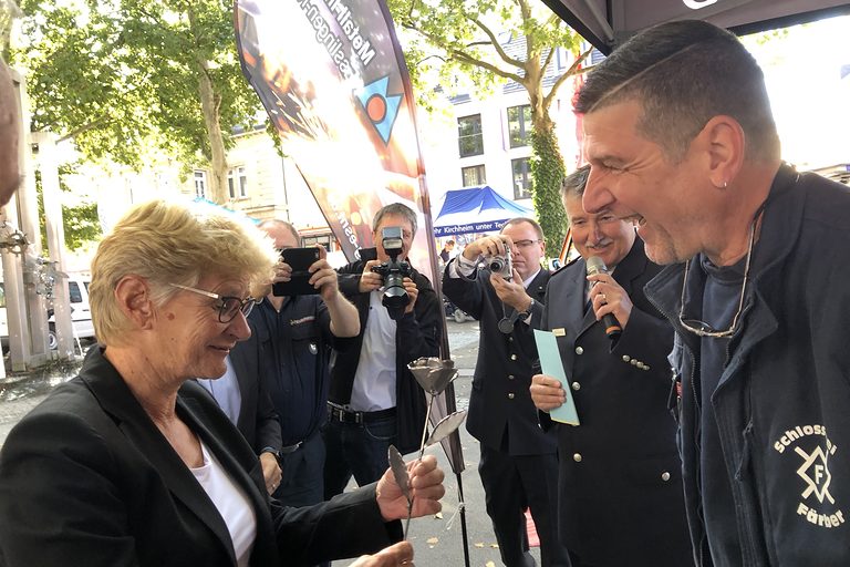 Bürgermeisterin Angelika Matt-Heidecker freut sich über eine Metallrose von Obermeister Oliver Färber (Metall-Innung Esslingen-Nürtingen).