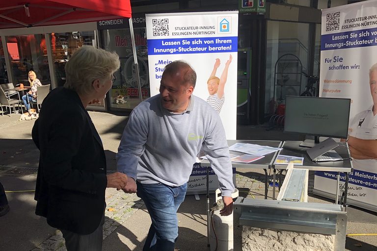 Stuckateur Stefan Haußmann begrüßt Bürgermeisterin Angelika Matt-Heidecker am Stand der Innung in Kirchheim.