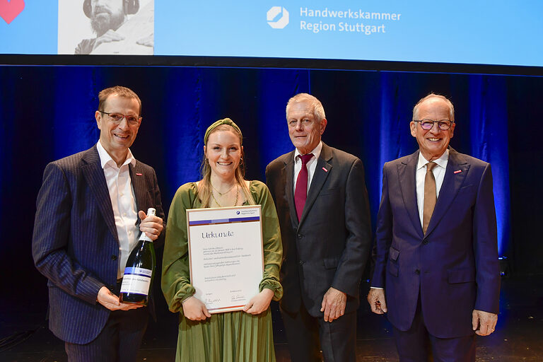 Sandra Mayer, Bestmeisterin im Schilder- und Lichtreklamehersteller-Handwerk, erhält von Vizepräsident Alexander Kotz (1.v.l.), Vizepräsident Peter Kudielka (2.v.r.) und Präsident Rainer Reichhold (1.v.r.) ihre Schmuckurkunde und eine Sektflasche. 