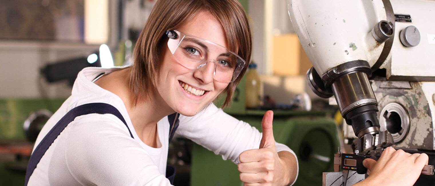 Symbolbild: QualitätsmanagementJunge Frau an Fräsmaschine mit Daumen nach oben